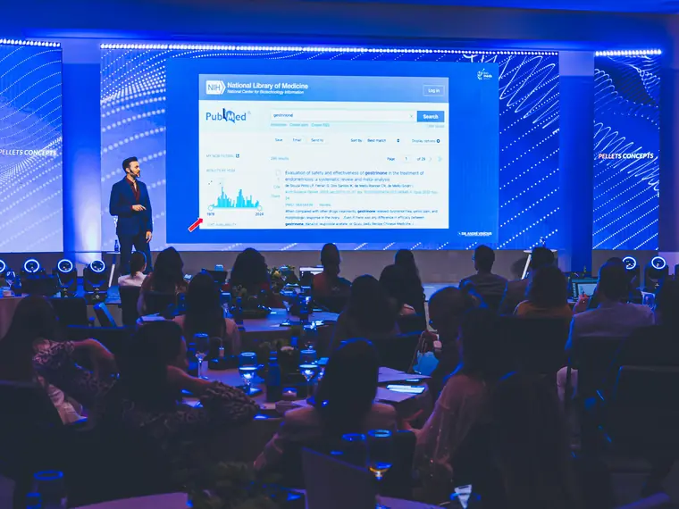 Palestra do Biomeds Pellets Concept, com plateia em mesas e apresentação projetada no telão