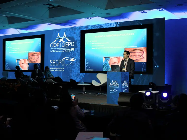 Palestrante no palco do congresso CIOP CIEPO 2025, com telões e plateia em Florianópolis