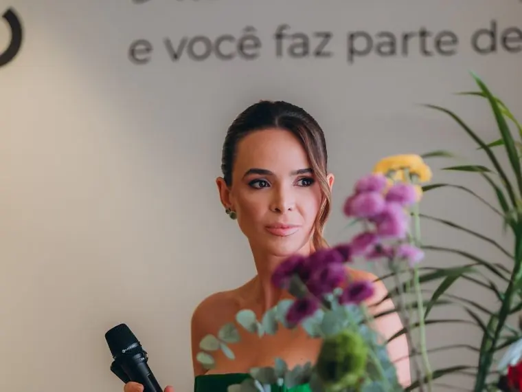 Médica com microfone em mesa florida, durante encontro do Clube Floreser